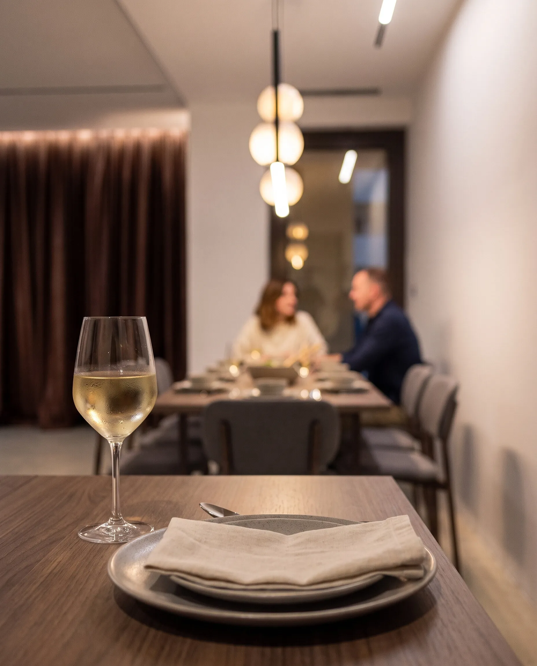 Dining room in the evening: a glass of wine, a couple talking by the window