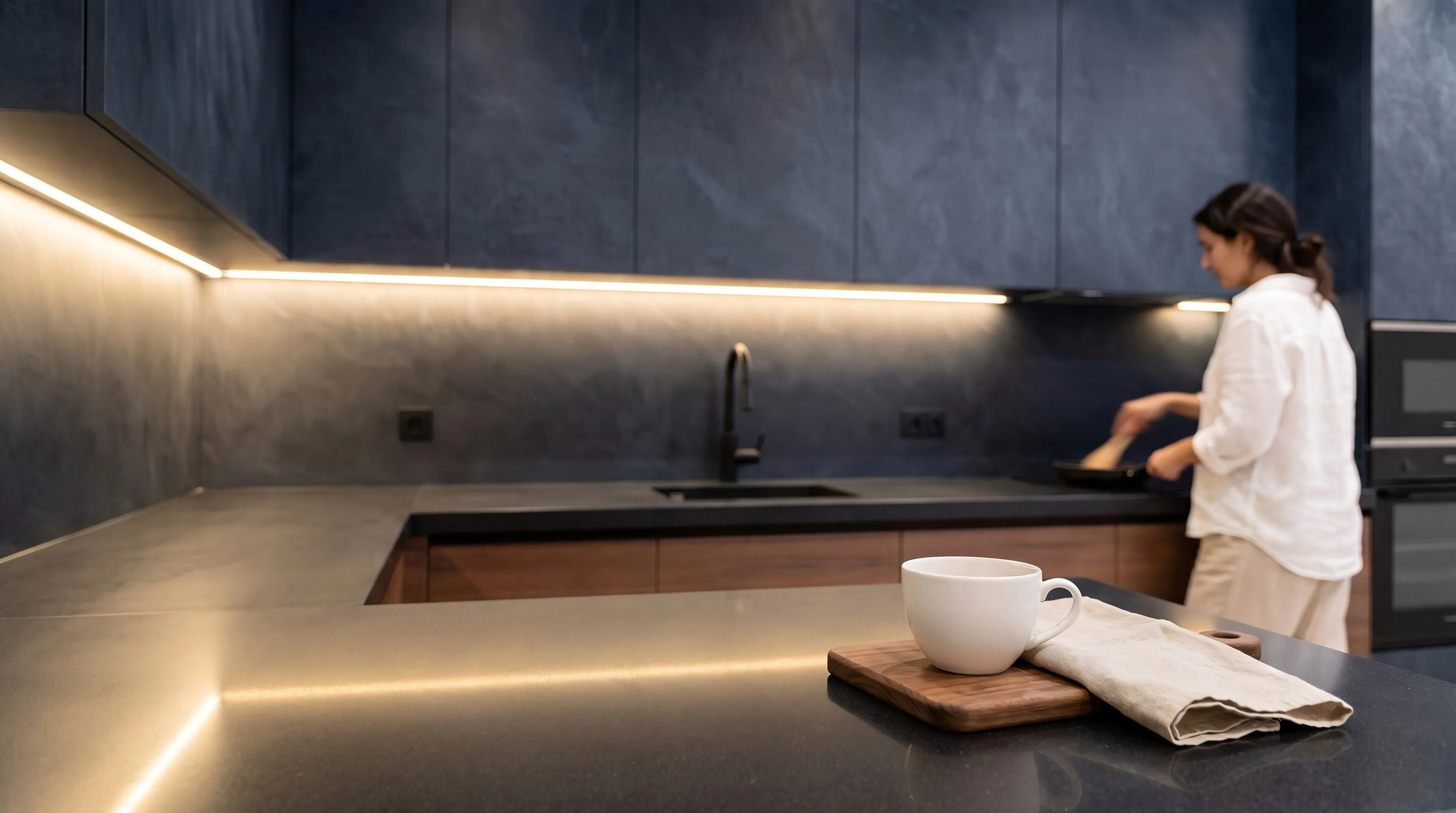 Kitchen: a cup of coffee on the counter, the owner cooking at the hob
